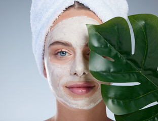 Woman, leaf and face mask for skincare in studio, vegan beauty and treatment on blue background....