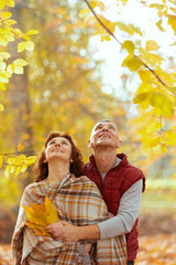 happy romantic couple in park with autumn leafs looking up