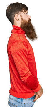 Redhead man with long beard wearing casual clothes looking to side, relax profile pose with natural face with confident smile.