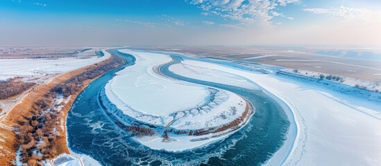 Fototapeta premium Frozen River Winding Through Snowy Landscape in Winter