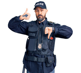 Young handsome man wearing police uniform doing thumbs up and down, disagreement and agreement expression. crazy conflict