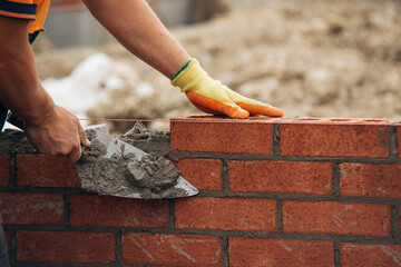 Construction Worker Laying Red Brick With Trowel and Mortar