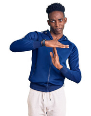 Young african american man wearing sportswear doing time out gesture with hands, frustrated and...