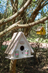 A white birdhouse with a pink ribbon hanging from it