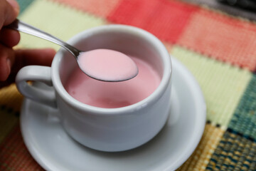 pink yogurt in white cup on table