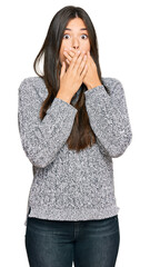 Young brunette woman wearing casual winter sweater shocked covering mouth with hands for mistake. secret concept.