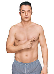 Fototapeta premium Handsome young man wearing swimwear shirtless pointing aside worried and nervous with forefinger, concerned and surprised expression