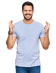 Fototapeta premium Young hispanic man wearing casual clothes gesturing finger crossed smiling with hope and eyes closed. luck and superstitious concept.
