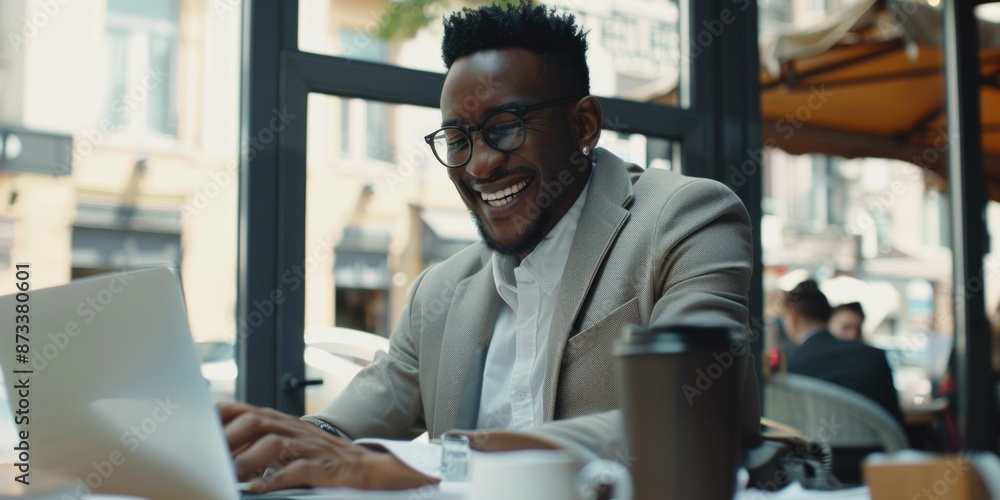 Poster a man is sitting at a table with a laptop and a cup of coffee. he is smiling and he is enjoying his 