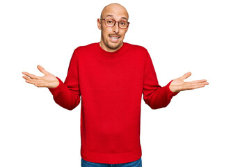 Bald man with beard wearing casual clothes and glasses clueless and confused expression with arms...