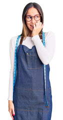 Beautiful brunette young woman dressmaker designer wearing atelier apron looking stressed and...