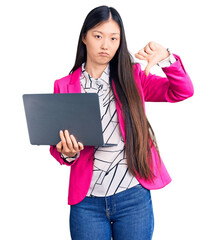 Young beautiful chinese woman using laptop with angry face, negative sign showing dislike with...