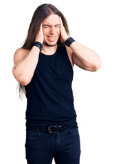 Young adult man with long hair wearing goth style with black clothes with hand on head, headache because stress. suffering migraine.