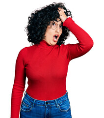 Young middle east girl wearing casual clothes and glasses surprised with hand on head for mistake,...
