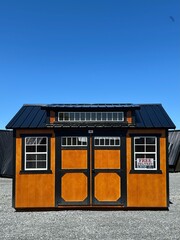 American style wooded shed. A shed is typically simple, single-story roofed structure in a back garden or on an allotment that is used for storage, hobbies, or as a workshop.