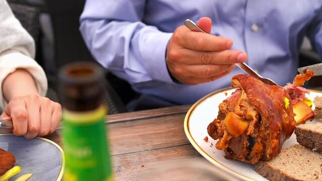Man eating Schweinehaxe (German Pork Knuckle) or Stinco at beer hall in Germany