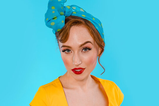 Woman With Polka Dot Headscarf and Red Lipstick Posing Against Blue Background