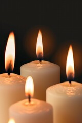 A close up of four candles with their flames visible. The candles are lit and the image conveys a sense of warmth and comfort