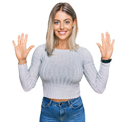 Beautiful blonde woman wearing casual clothes showing and pointing up with fingers number ten while smiling confident and happy.