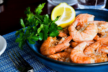 Steamed Shrimp with lemon on a blue plate with a splash of greenery
