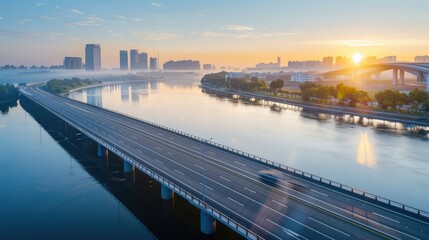 A modern bridge road over a large river at sunrise, with the water reflecting the warm glow of the sun and the city skyline in the background.