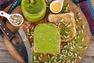 Tasty pistachio cream in jar and nuts on wooden table, flat lay. Pistachio nut butter in glass jar....