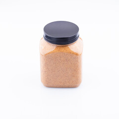 A clear plastic jar filled with creamy almond butter, with a black plastic lid, sits on a white background. The jar is rectangular in shape and appears to be full of smooth, light-brown almond butter.