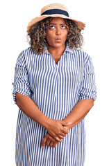 Young african american plus size woman wearing summer hat making fish face with lips, crazy and comical gesture. funny expression.