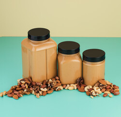 Three different sized jars of smooth creamy cashew butter against dual-tone pastel background, with...