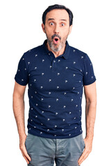 Obraz premium Middle age handsome man wearing casual polo scared and amazed with open mouth for surprise, disbelief face