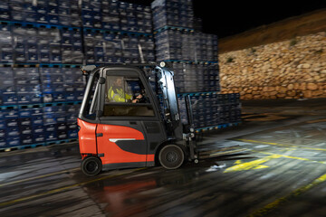 Forklift operator driving forklift truck outdoors at night with headlight © Eomer2010