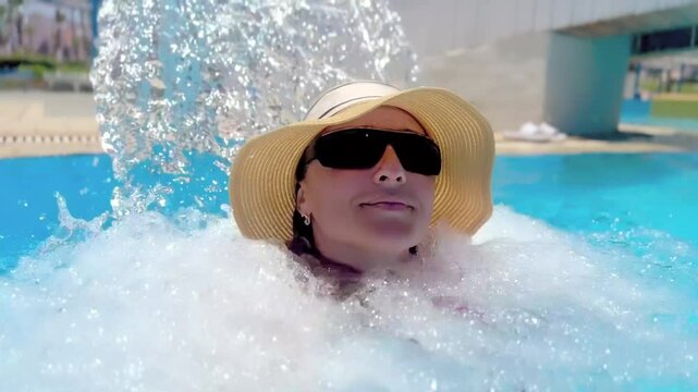 Portrait of a woman under a waterfall in a swimming pool