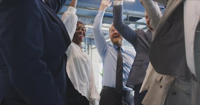 Team of business people stands in a circle, stacking hands in unity and celebration of teamwork in the office. Group collaboration, solidarity, and collective success in achieving business goals.