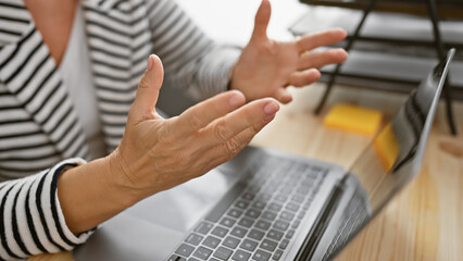 A close-up of a middle-aged woman explaining something in an office, her hands gesturing with a...