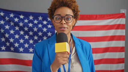 African american woman speaking with microphone against us flag backdrop