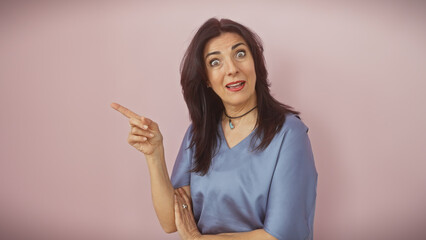 Surprised middle-aged hispanic woman pointing isolated against a pink background