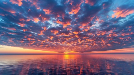 A vibrant morning sky with layers of scattered stratocumulus clouds reflecting the fiery hues of dawn above a tranquil sea.
