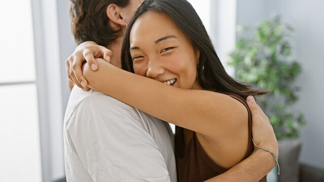 A loving embrace between a man and a woman in a bright modern living room - Powered by Adobe