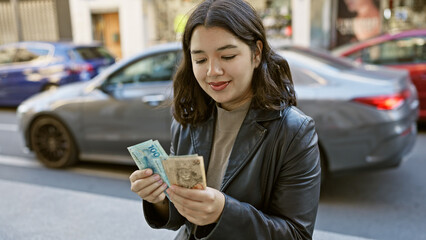 Young woman counts brazilian reais on a bustling city street evoking urban finance and travel...