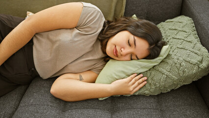 A serene young woman asleep on a sofa with plush pillows in a cozy living room