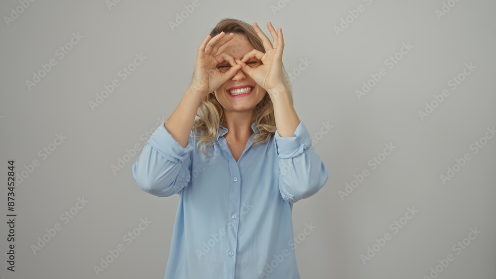 Canvas Prints a cheerful blonde woman playfully making goggles with her fingers on a white background, depicting j