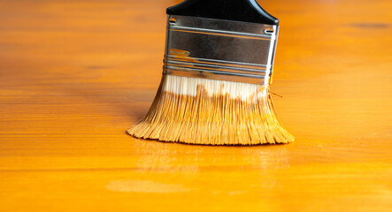 Painting table with brown enamel, brush in hand close-up, painting wood furniture process with brownish dye