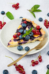 A piece of shortbread pie with blueberries and mint. Seasonal summer baking. Top view, on a light background.