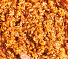 Close-up texture of steamy jambalaya with rice, sausage, and spices representing louisiana cuisine.