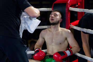 Cornered boxer receives strategic advice from trainer during intense bout.
