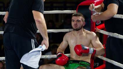 Cornered boxer receives strategic advice from trainer during intense bout.