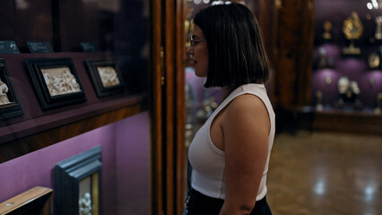 Young beautiful hispanic woman looking at art exhibition at imperial treasure museum in Vienna