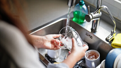 Young beautiful hispanic woman washing plates at the kitchen
