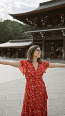 Beautiful hispanic woman joyfully embraces freedom, smiling with open arms, looking around meiji temple