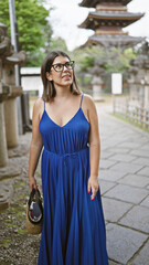 Beautiful young hispanic woman wearing glasses standing smiling looking around at ueno park temple